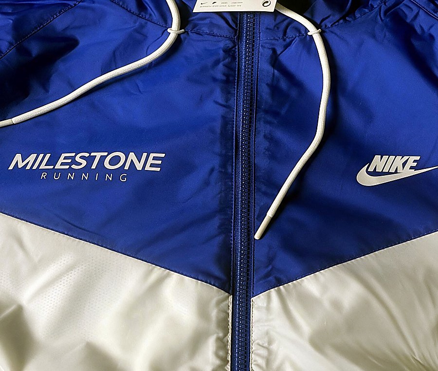 Blue and white Nike Windrunner jacket printed with the Milestone Running logo