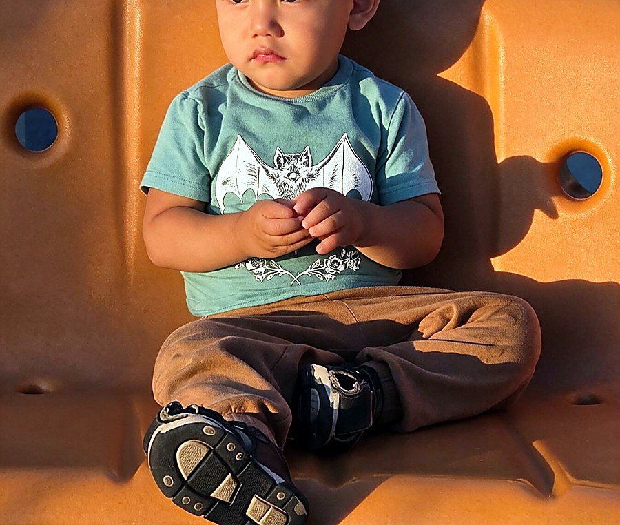 Toddler sitting on an orange chair wearing a printed tee