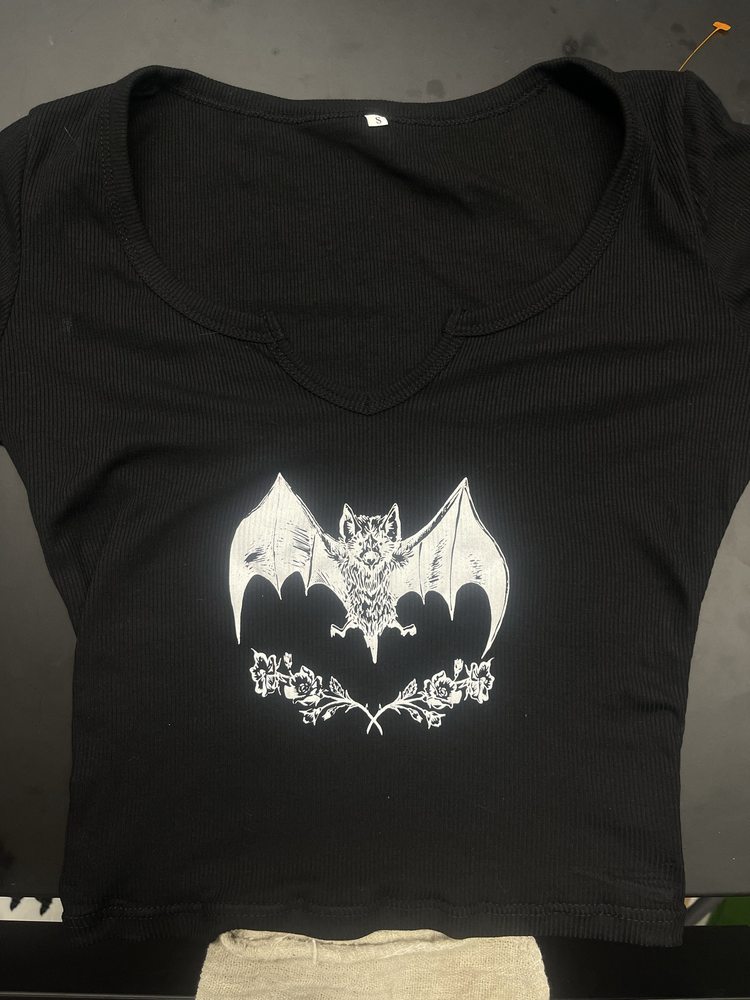 Fine-line bat and roses illustration printed in white on a black ribbed crop top