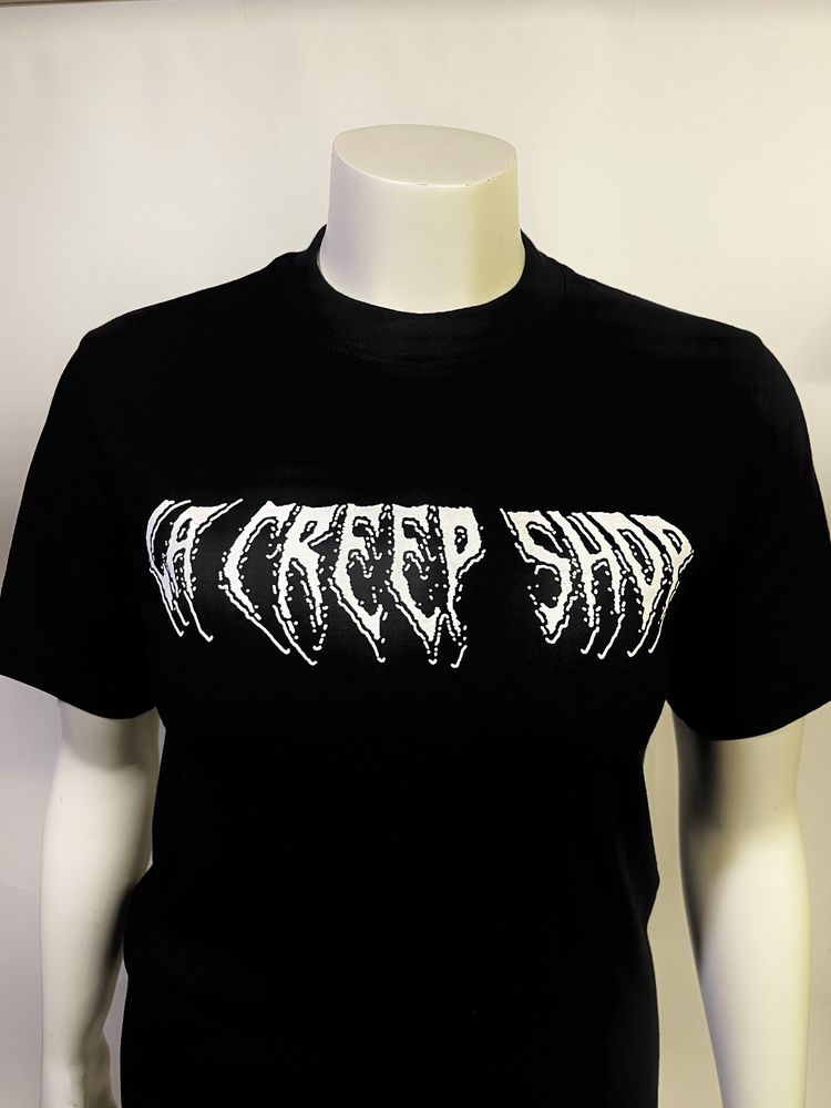 White horror-style drip lettering reading LA Creep Shop on a black tee