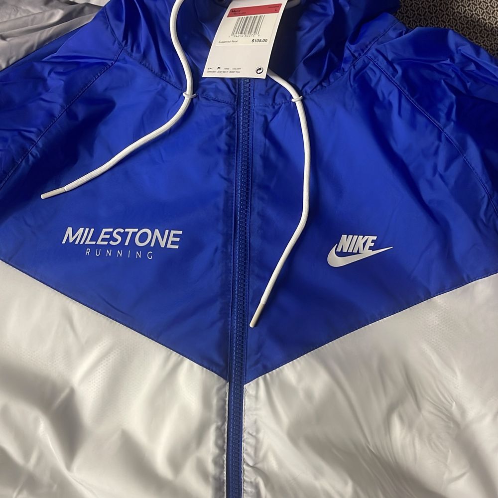Blue and white Nike Windrunner jacket printed with the Milestone Running logo